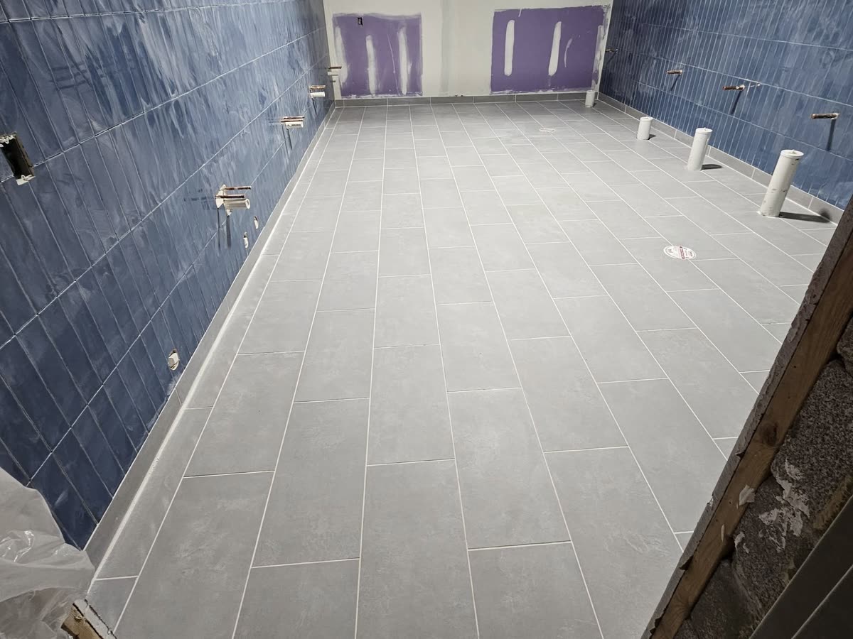 Blue wall tile and grey floor tile in a restroom