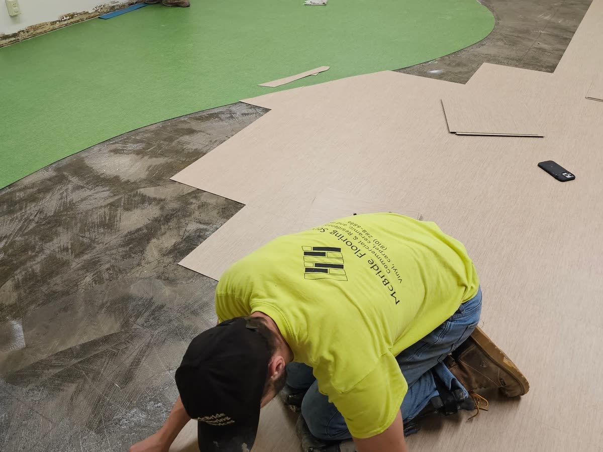 Installer laying sheet vinyl with a hi-vis McBride shirt