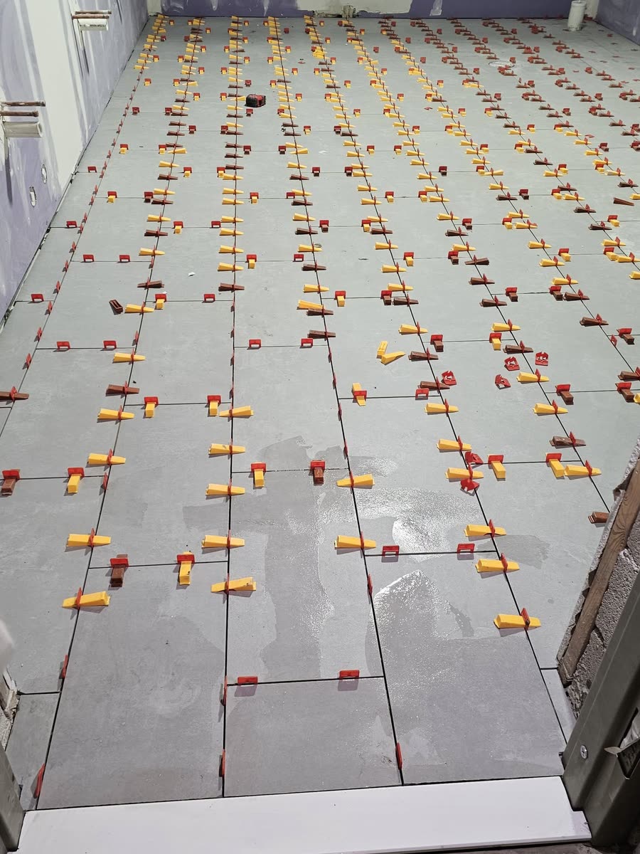 Large-format floor tile with leveling clips still on